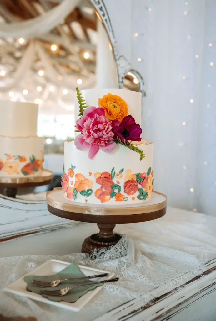 A colorful wedding cake sits on a dresser and is decorated with flowers at Old Coon Creek Wedding Venue in Beloit, Wisconsin