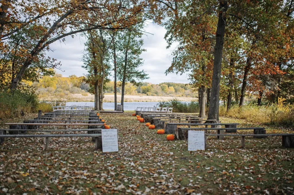 The waterfront ceremony site showing rustic seating in autumn at Old Coon Creek Wedding Venue in Beloit, Wisconsin