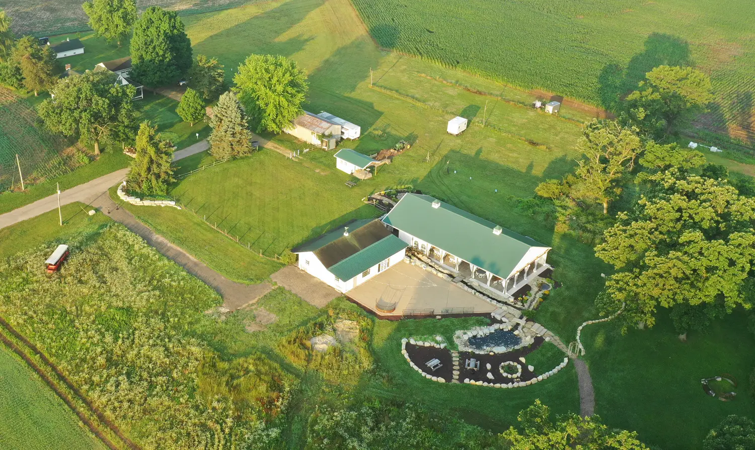 An aerial view of the Old Coon Creek pavilion, farmhouse and grounds on a summer evening